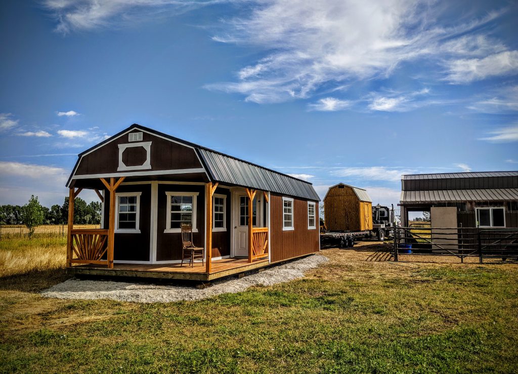 Lofted barn converted into a deluxe cabin with porch, showing how premium add-ons significantly increase shed cost and usability. Perfect representation of a high-end shed upgrade within the 2026 shed pricing process.