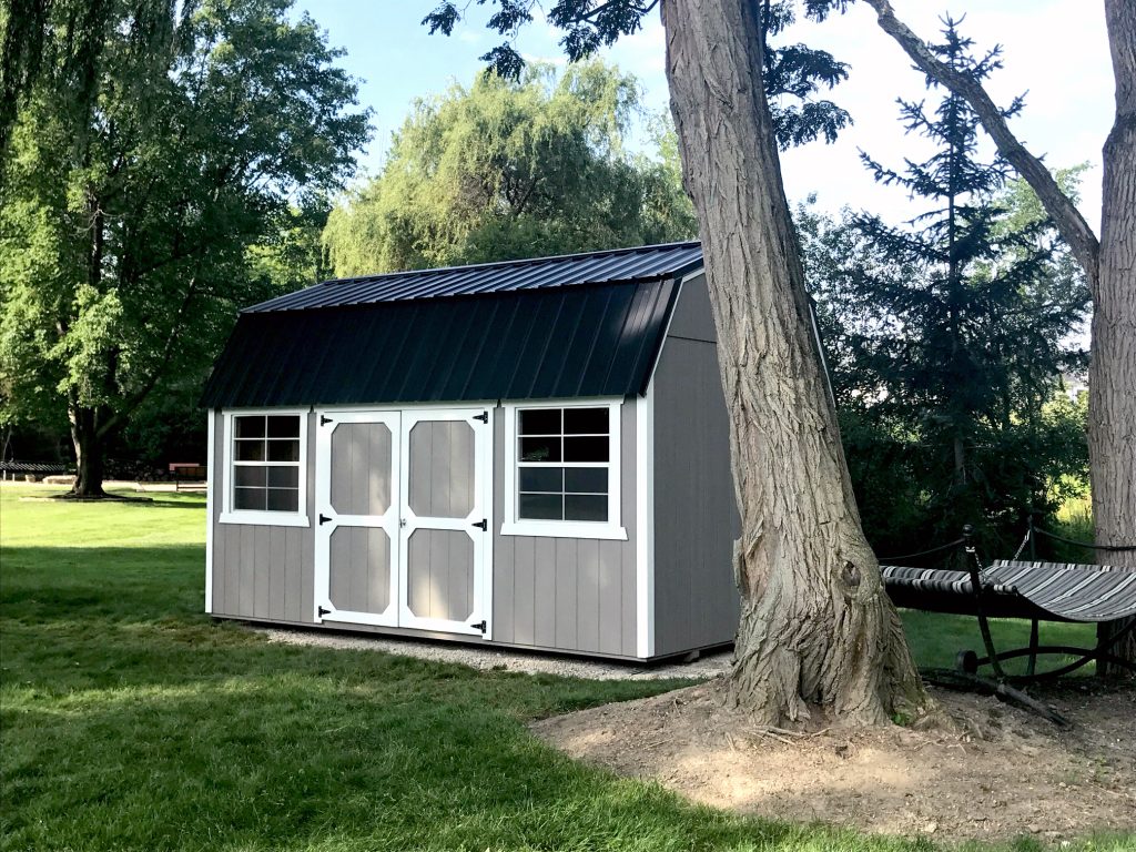 Gray lofted barn shed with gambrel roof and double doors, highlighting a storage building option with added overhead space that impacts shed pricing. Demonstrates a mid-range shed style commonly chosen for increased storage capacity and value.