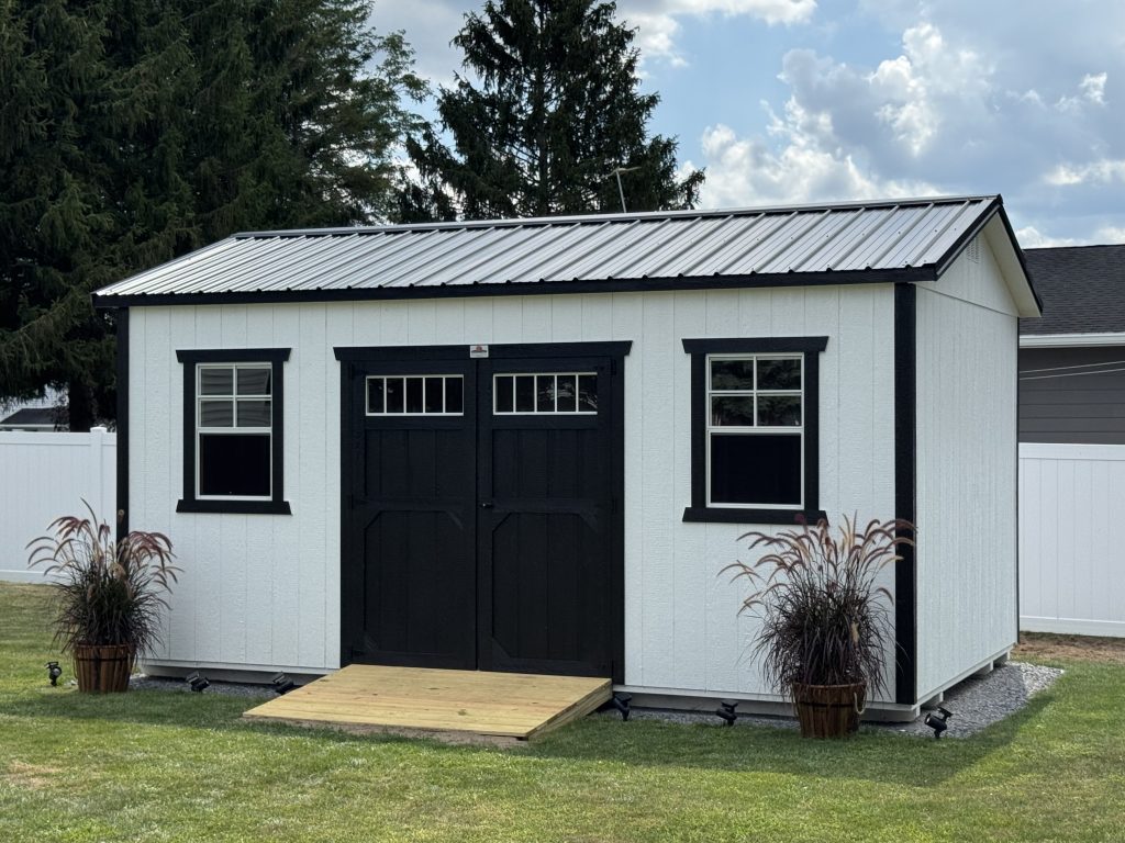 Modern white utility shed with black trim and double doors, showcasing a popular backyard storage shed style and base pricing starting point. Ideal example of a standard shed size and design that influences overall shed cost in 2026 pricing guide.